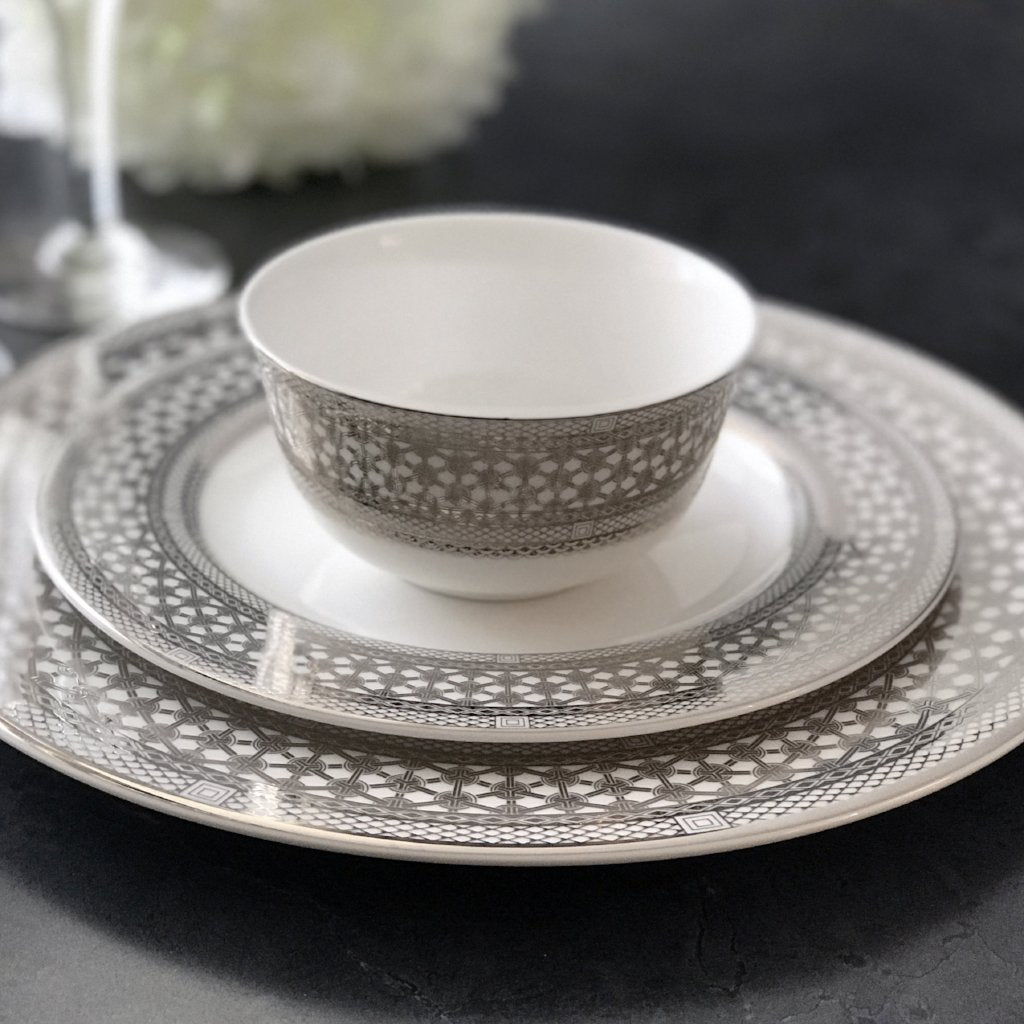 A Caskata Artisanal Home Hawthorne Ice Platinum Dinner Plate and white dinner set with a cup and saucer.