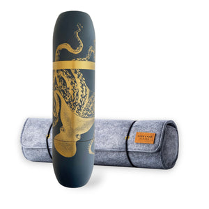 The Caskata X High Camp Flasks Lucy Dark Blue Flask stands upright, featuring a gold octopus design, in front of its gray felt case with a brown leather patch.