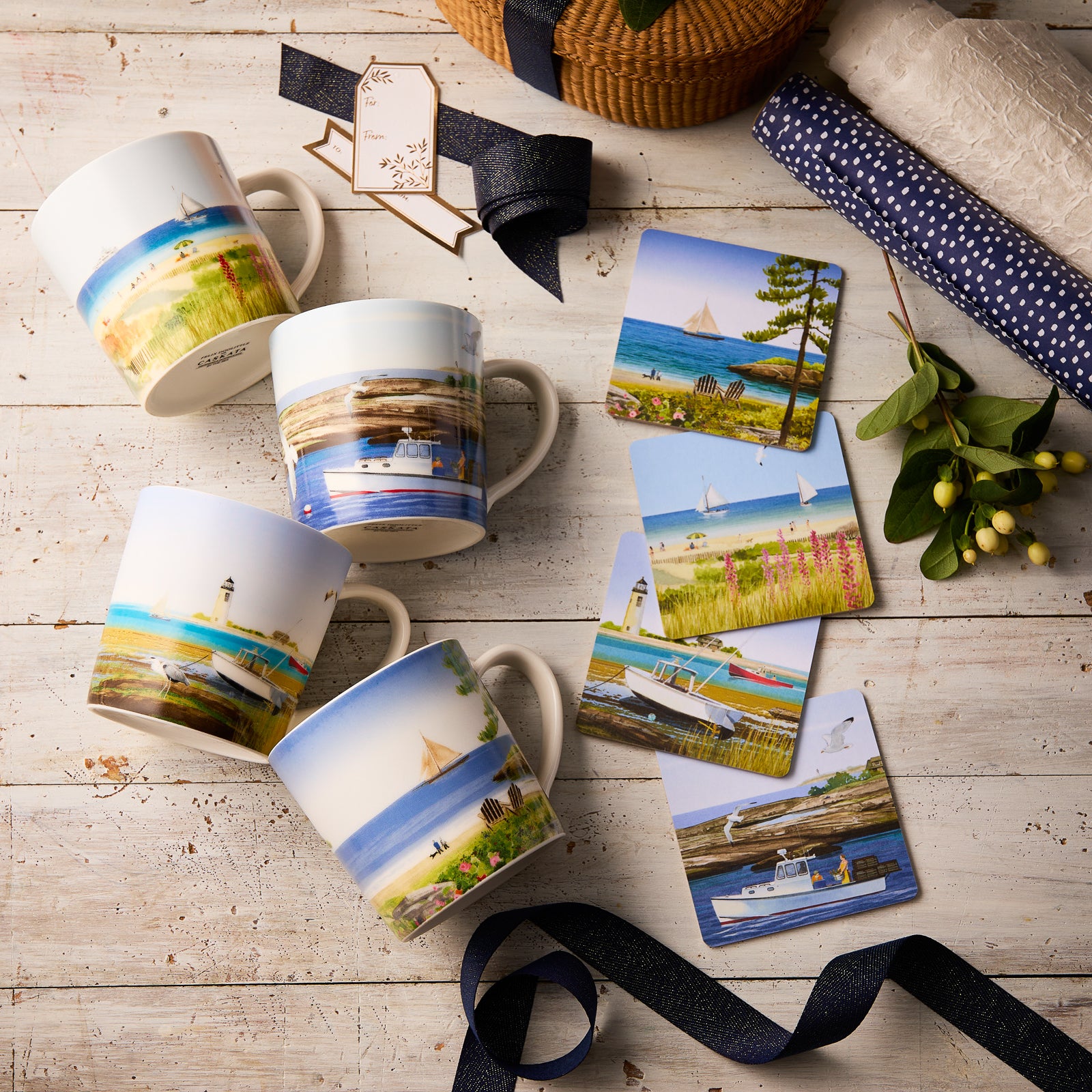 The "Down East" Bundle by Felix Doolittle—featuring watercolor mugs and coastal scenery coasters—is displayed on a rustic white table with gift tags, ribbon, and greenery for a charming New England summer vibe.
