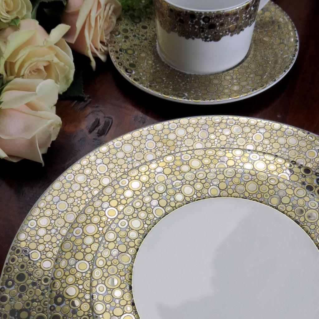 A Ellington Shimmer Gold &amp; Platinum Dinner Plate and cup shimmer on a table with hints of Caskata Artisanal Home&#39;s platinum influence, creating a symphony of random notes.