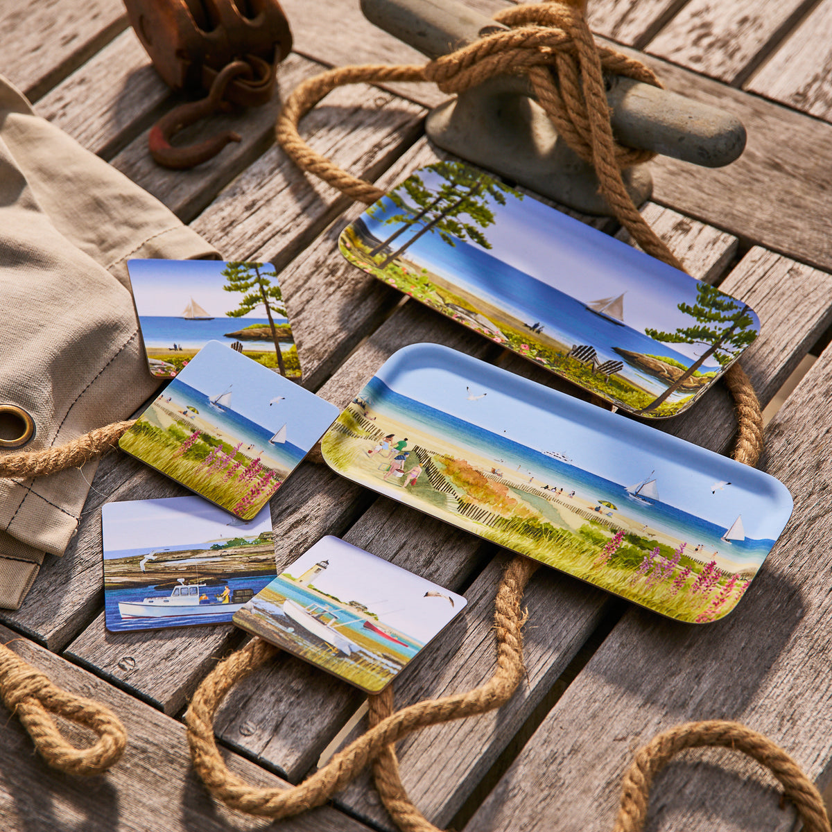 The Caskata X Felix Doolittle Beach Dunes Small Rectangular Tray by Caskata features colorful beach scenes and sits on a wooden surface with nautical accents—perfect for adding vibrant summer style to your home decor.