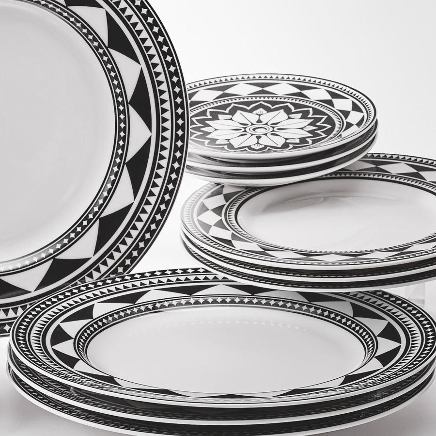 A 16 piece set of Fez Table for 4 black and white plates on a white surface made by Caskata.