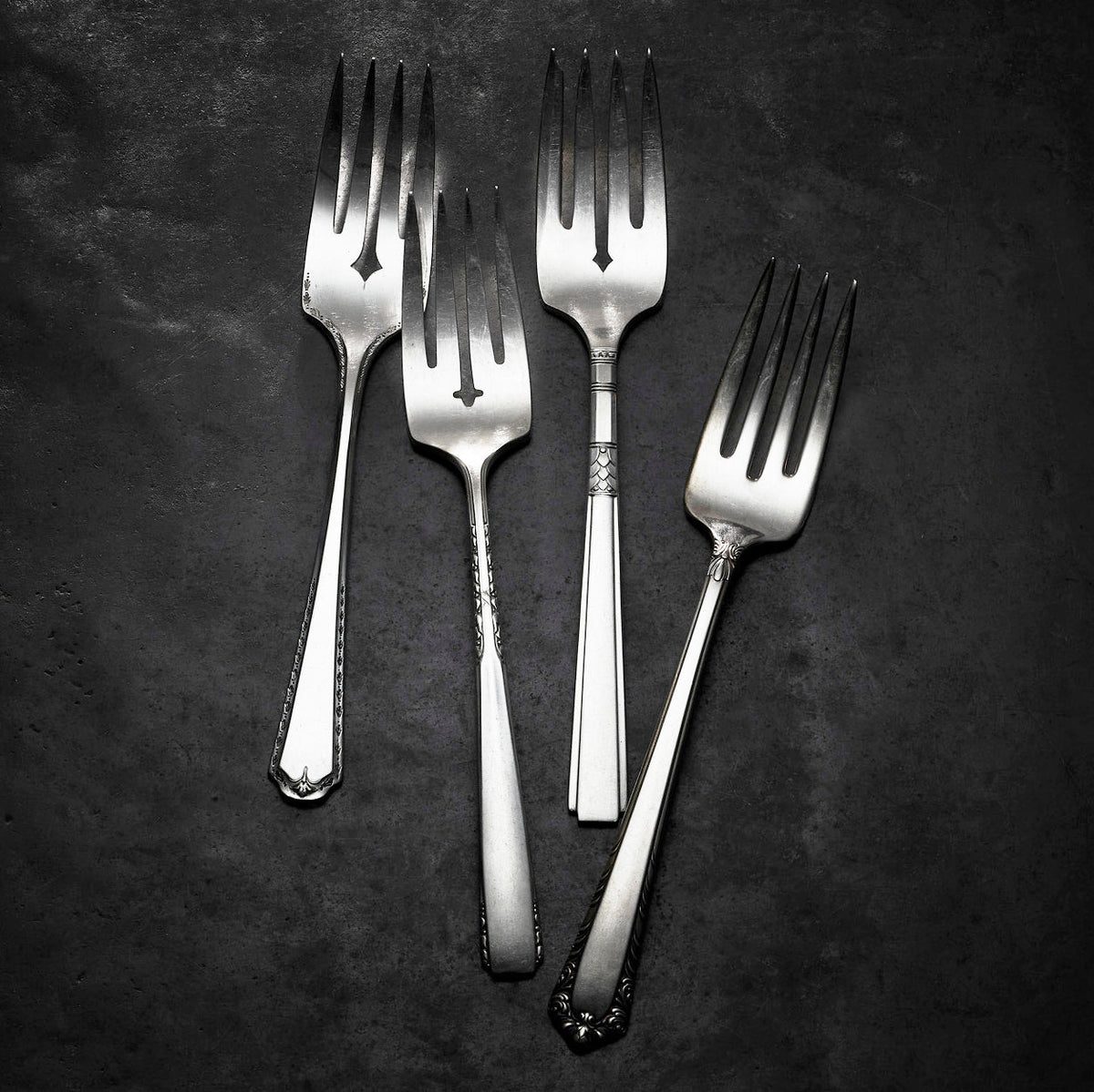 Three Brimfield Vintage Salad Forks by Caskata on a black surface.