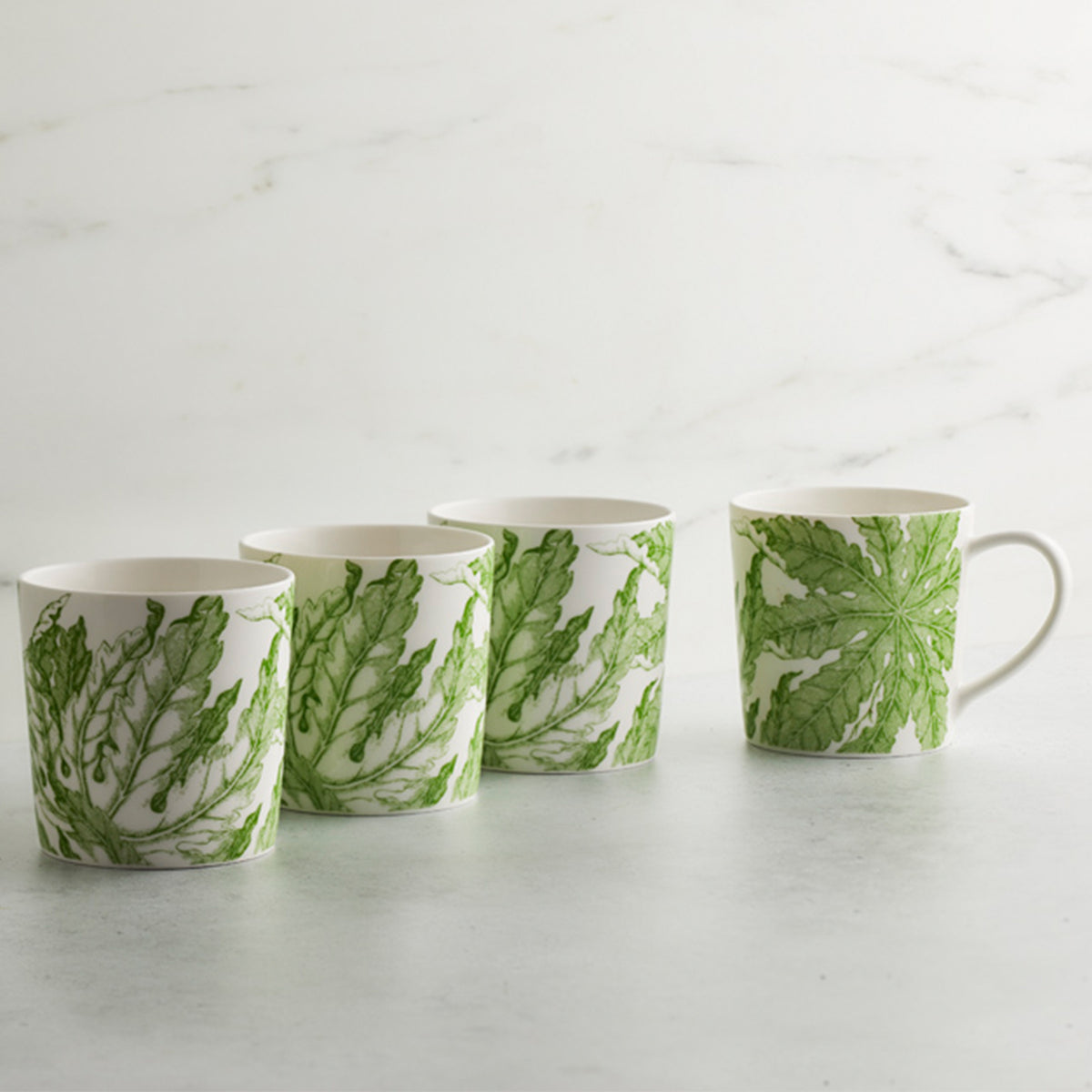 Four Freya mugs by Caskata Artisanal Home with leaves on them, symbolizing fertility.