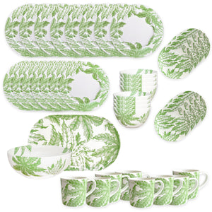 The Caskata Freya Ultimate Set is a 42-piece porcelain dinnerware collection with plates, bowls, and mugs in a green leafy pattern on white. Dishwasher and microwave safe, it's beautifully arranged on a white surface.
