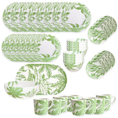 The Caskata Freya Ultimate Set is a 42-piece porcelain dinnerware collection with plates, bowls, and mugs in a green leafy pattern on white. Dishwasher and microwave safe, it's beautifully arranged on a white surface.