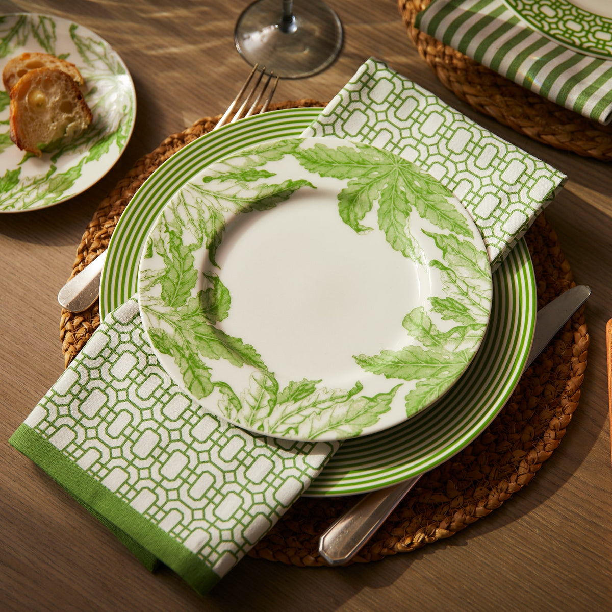 A Caskata Newport Garden Gate Dinner Napkins in Green Set/4 paired with a matching dinner napkin.
