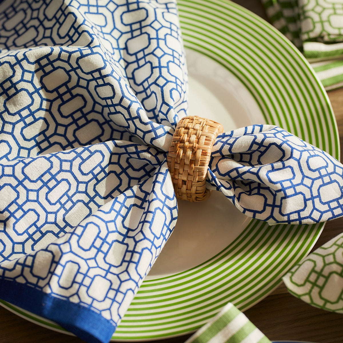 A signature blue Caskata Newport Garden Gate dinner napkin on a plate.