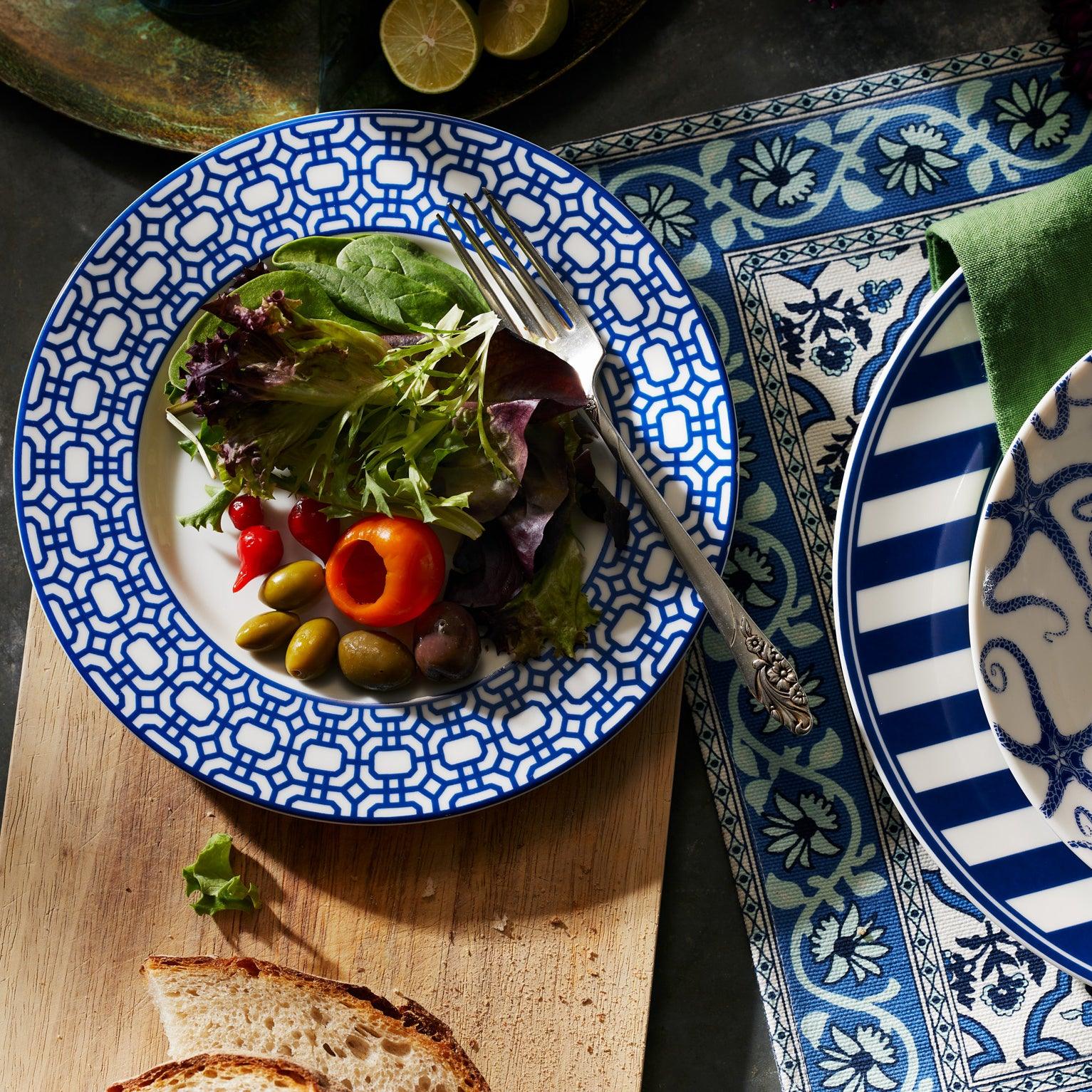 The Caskata Newport Garden Gate Table for 8 is a stylish, contemporary 24-piece porcelain dinnerware set with eight dinner plates, eight geometric salad plates, and two bowls with blue stripes—perfect for any table.