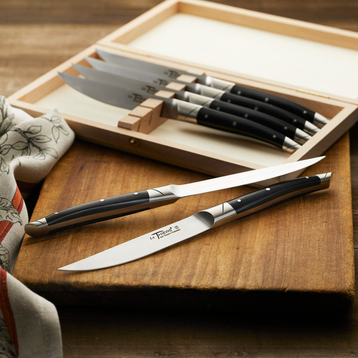 A Goyon-Chazeau Black Paperstone Steak Knives Boxed Set/6 on a cutting board.