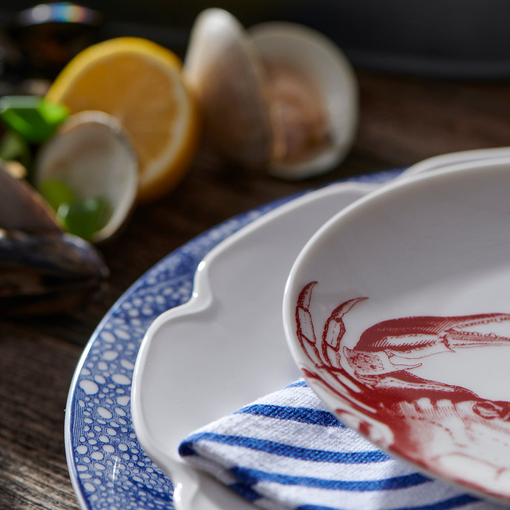 A Grace White Buffet Plate by Caskata Artisanal Home, with a polished lobster on it.