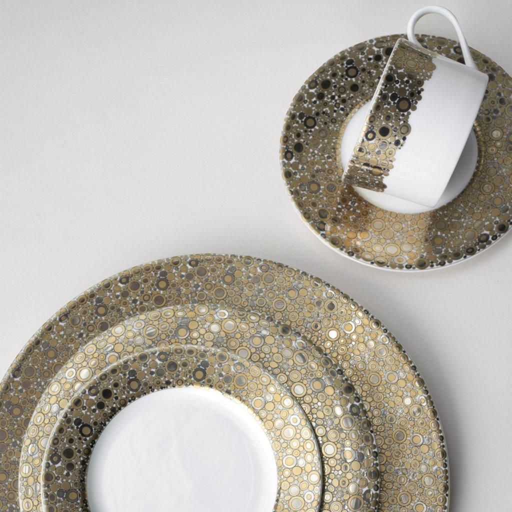 A set of Caskata Artisanal Home&#39;s Ellington Shimmer Gold &amp; Platinum Cups and Saucers, featuring elegant white bone china with matching gold and black patterned rims, displayed on a light surface.
