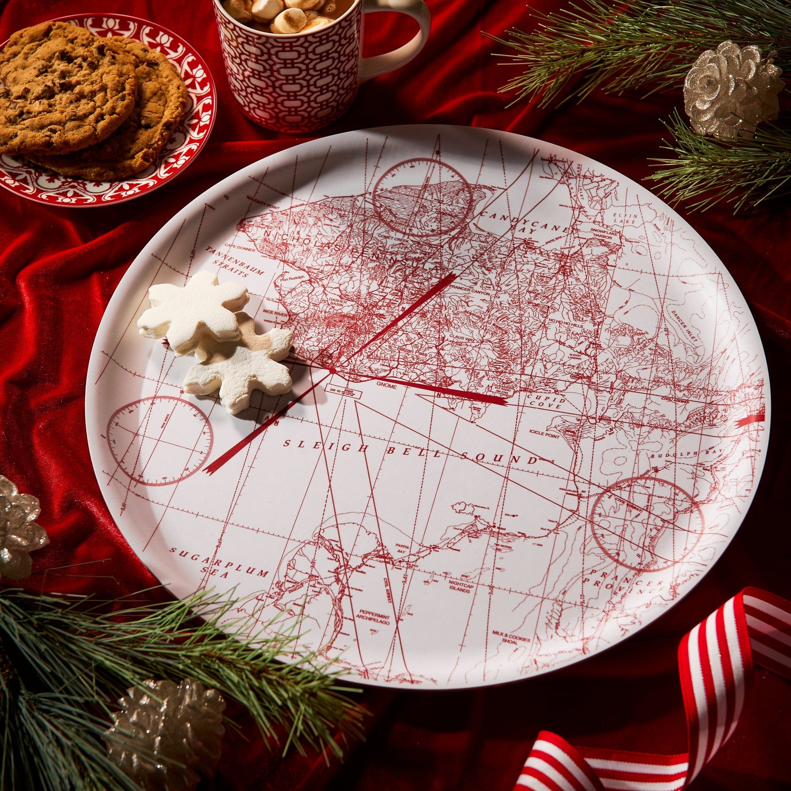 The Caskata White Holiday Hunt Large Round Tray is a decorative birchwood tray made in Finland, showcasing a red map-style North Pole illustration with whimsical spots like Candy Cane, Sleigh Bell Sound, and Sugarplum Sea.