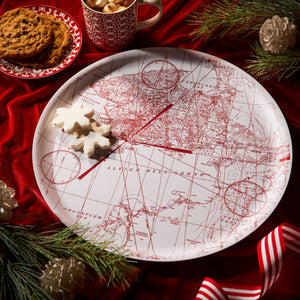 The Caskata White Holiday Hunt Large Round Tray holds two star-shaped cookies, set on a red tablecloth with more cookies, a mug, pine branches, and ribbon nearby.
