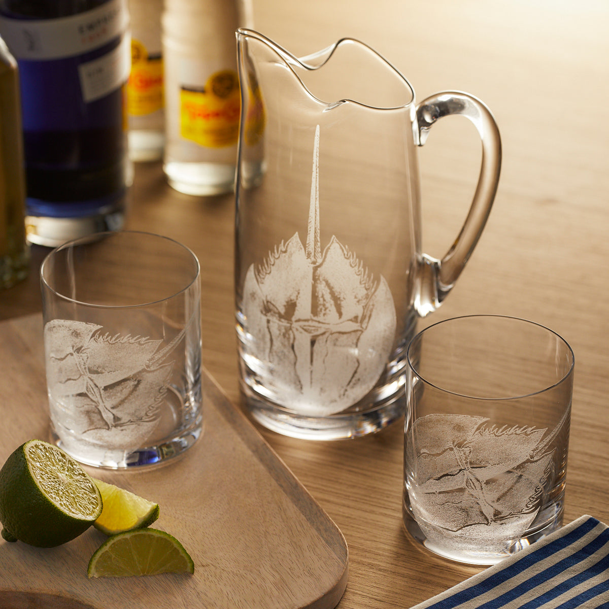 A Caskata Horseshoe Crab Small Pitcher and two glasses on a cutting board.