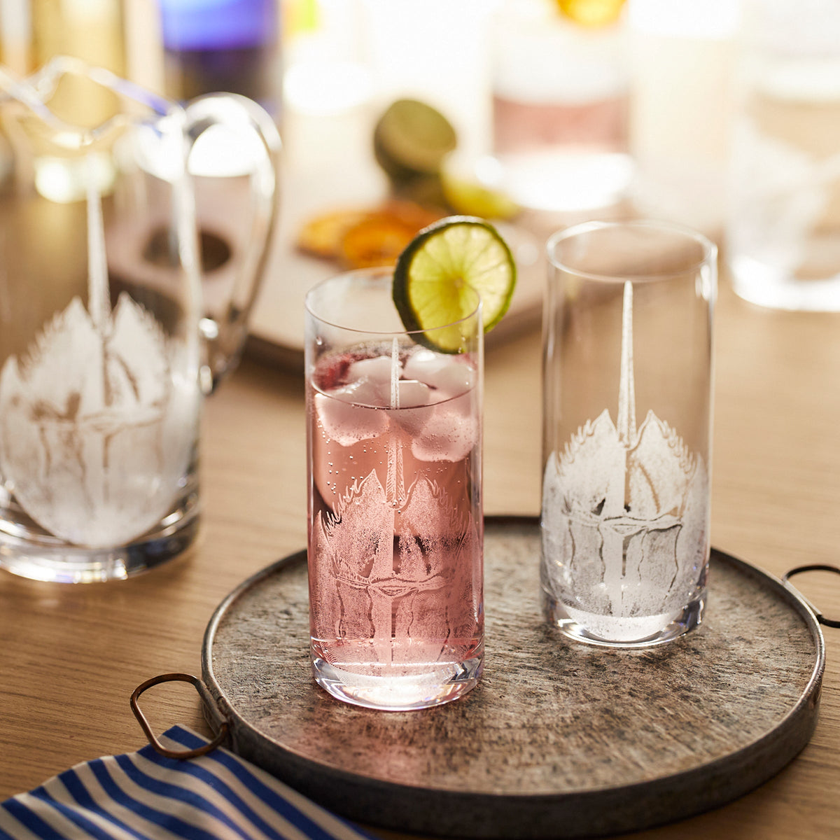 A tray with Caskata Horseshoe Crab Highball Glasses and a pitcher on it.