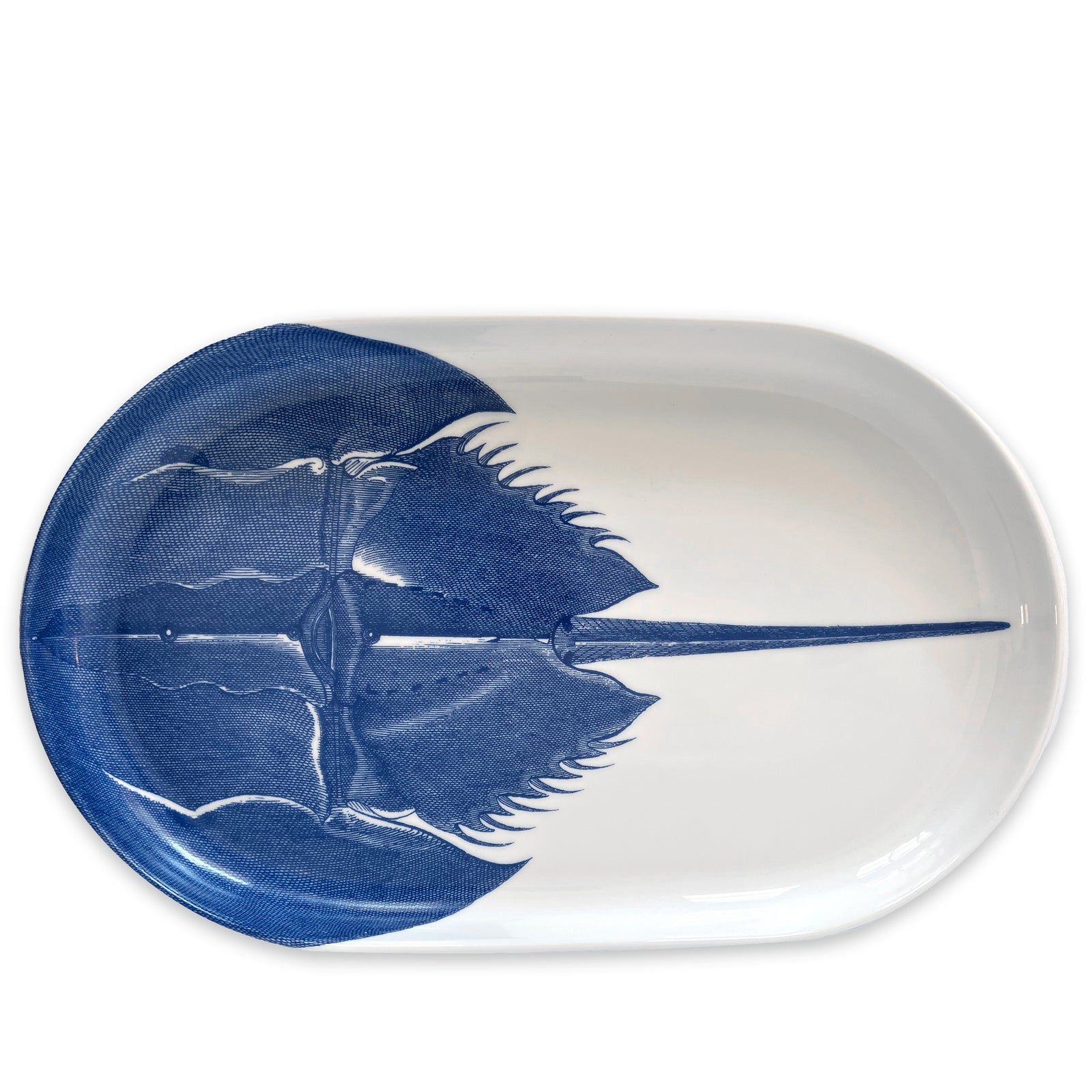 Introducing the Caskata Horseshoe Crab Large Coupe Oval Platter, a stunning white porcelain piece adorned with a blue illustration of the ancient sea creature, the horseshoe crab.