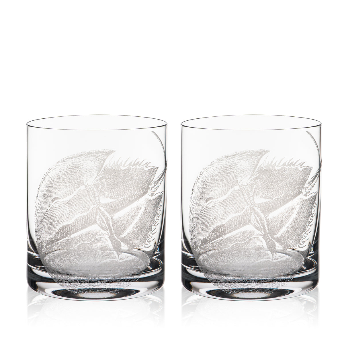 Caskata&#39;s Horseshoe Crab Rocks Glasses are two clear glass tumblers with elegant leaf designs, crafted using a sand-etching technique. These lead-free crystal pieces bring sophistication to any table.