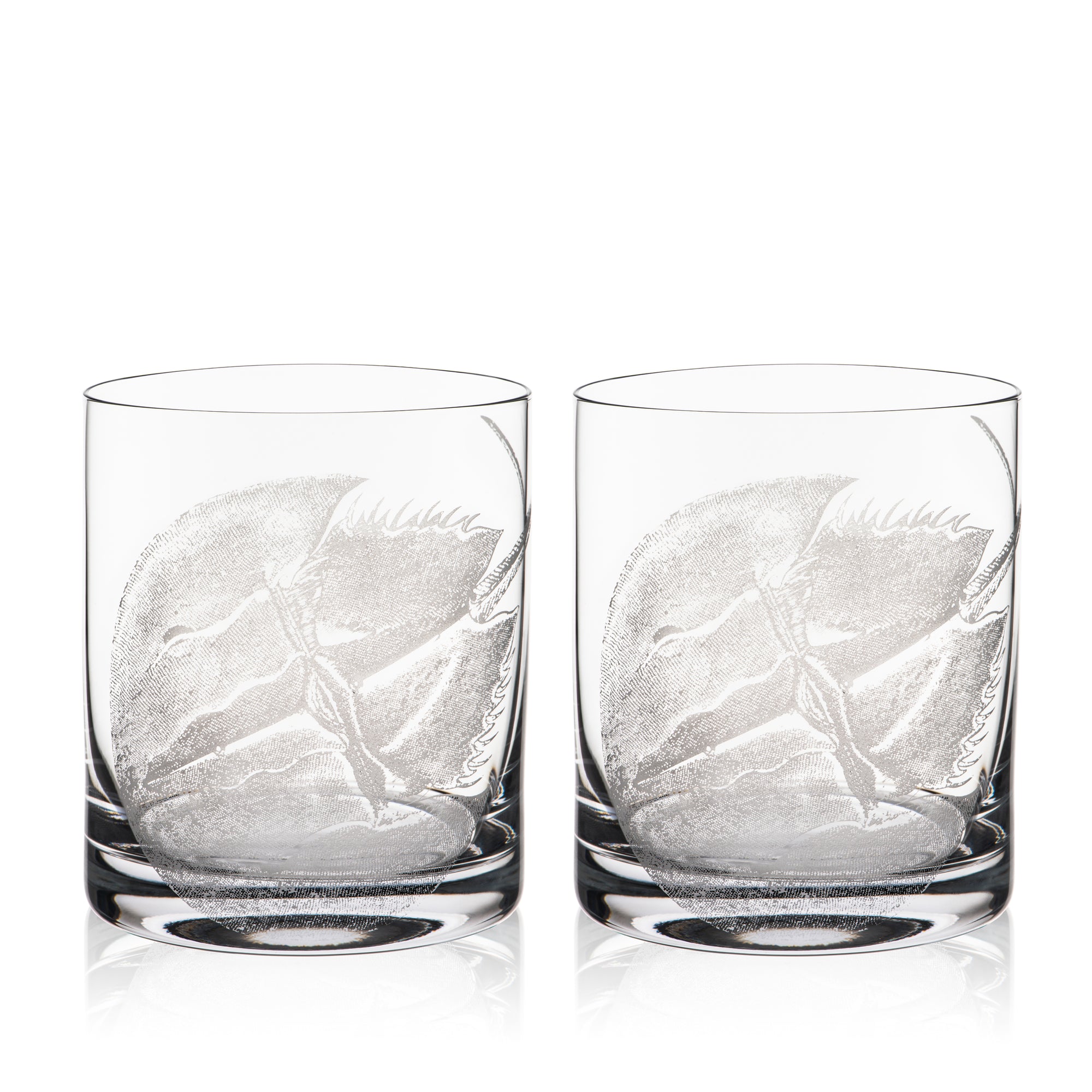 Caskata's Horseshoe Crab Rocks Glasses are two clear glass tumblers with elegant leaf designs, crafted using a sand-etching technique. These lead-free crystal pieces bring sophistication to any table.
