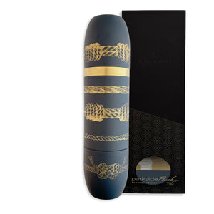 A dark blue, cylindrical Caskata x High Camp Sailor's Knots Wine Flask with gold rope design stands beside a black rectangular box labeled "parkside Fuel limited edition 750.