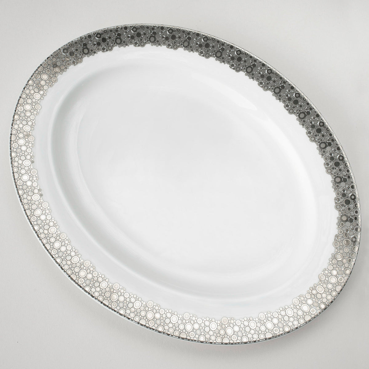 A white Ellington Shine Platinum Oval Rimmed Platter from Caskata Artisanal Home with a black and platinum pattern.