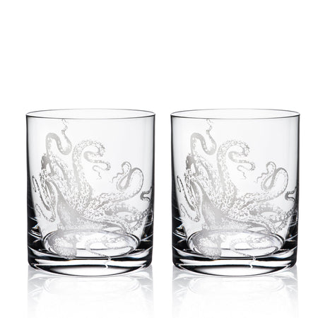 Two Lucy Rocks Glasses, crafted from exquisite crystal glassware by Caskata Artisanal Home, feature intricate octopus designs created using the sand-etching technique. Placed side by side, they merge elegance with a touch of marine mystique.
