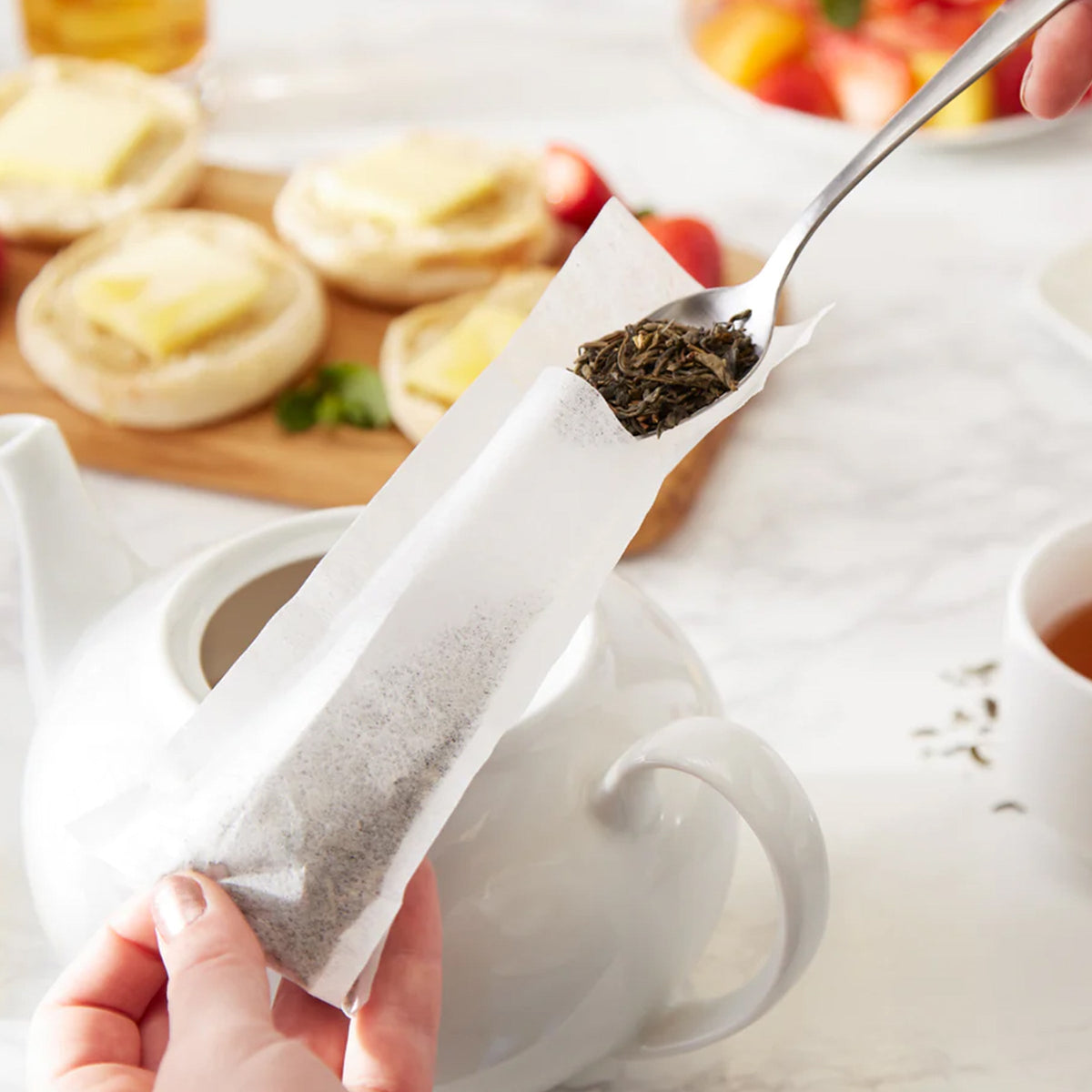 An individual is pouring loose leaf tea into a RSVP International Large Tea Filter.