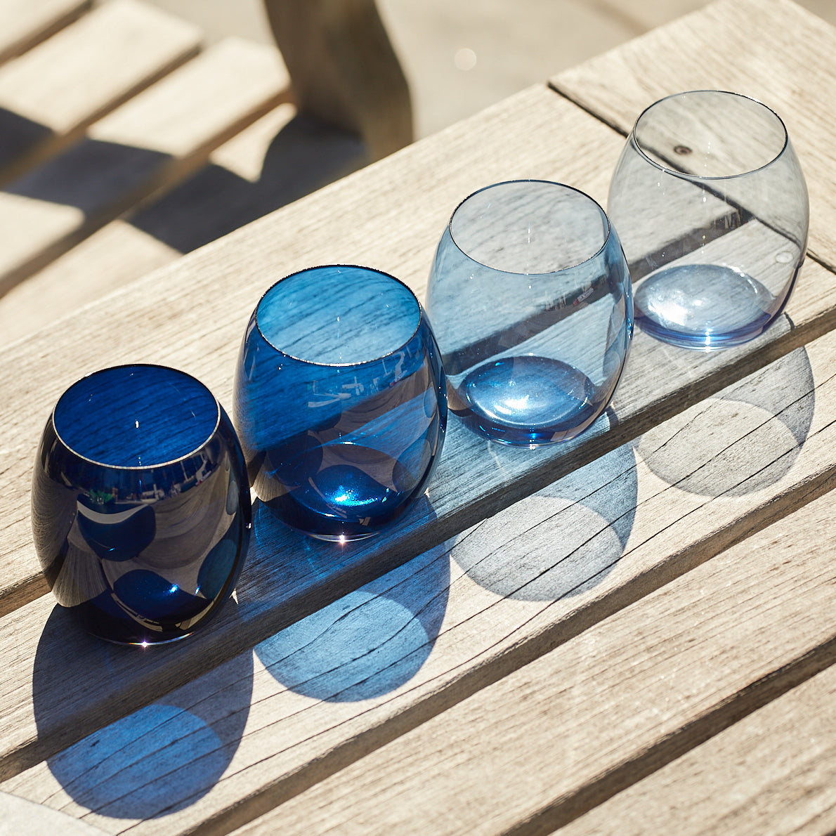 Three Les Nuages Blue Ombré Glasses Set of 4 on a wooden table.