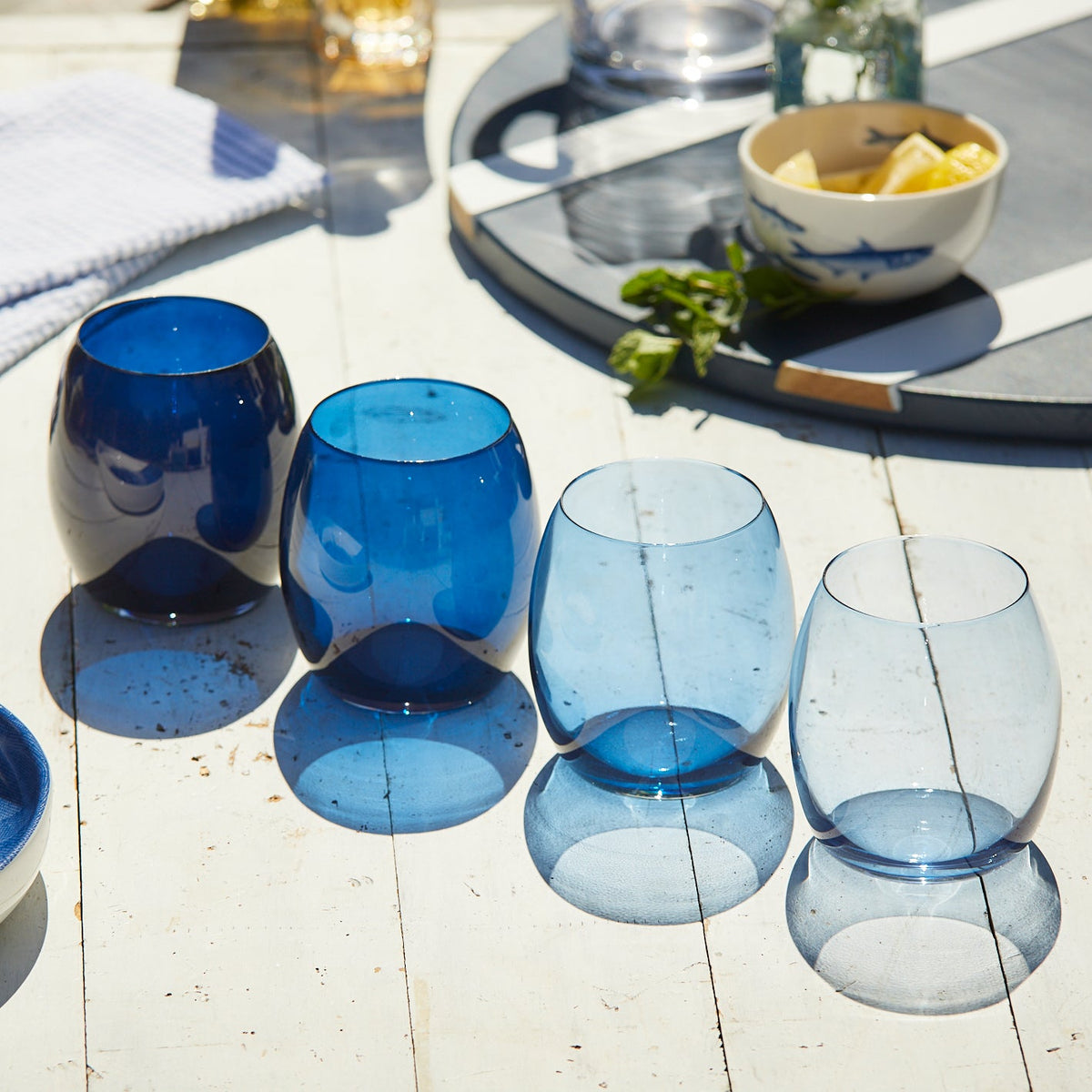 A set of Les Nuages Blue Ombré Glasses Set of 4 by Caskata on a table.