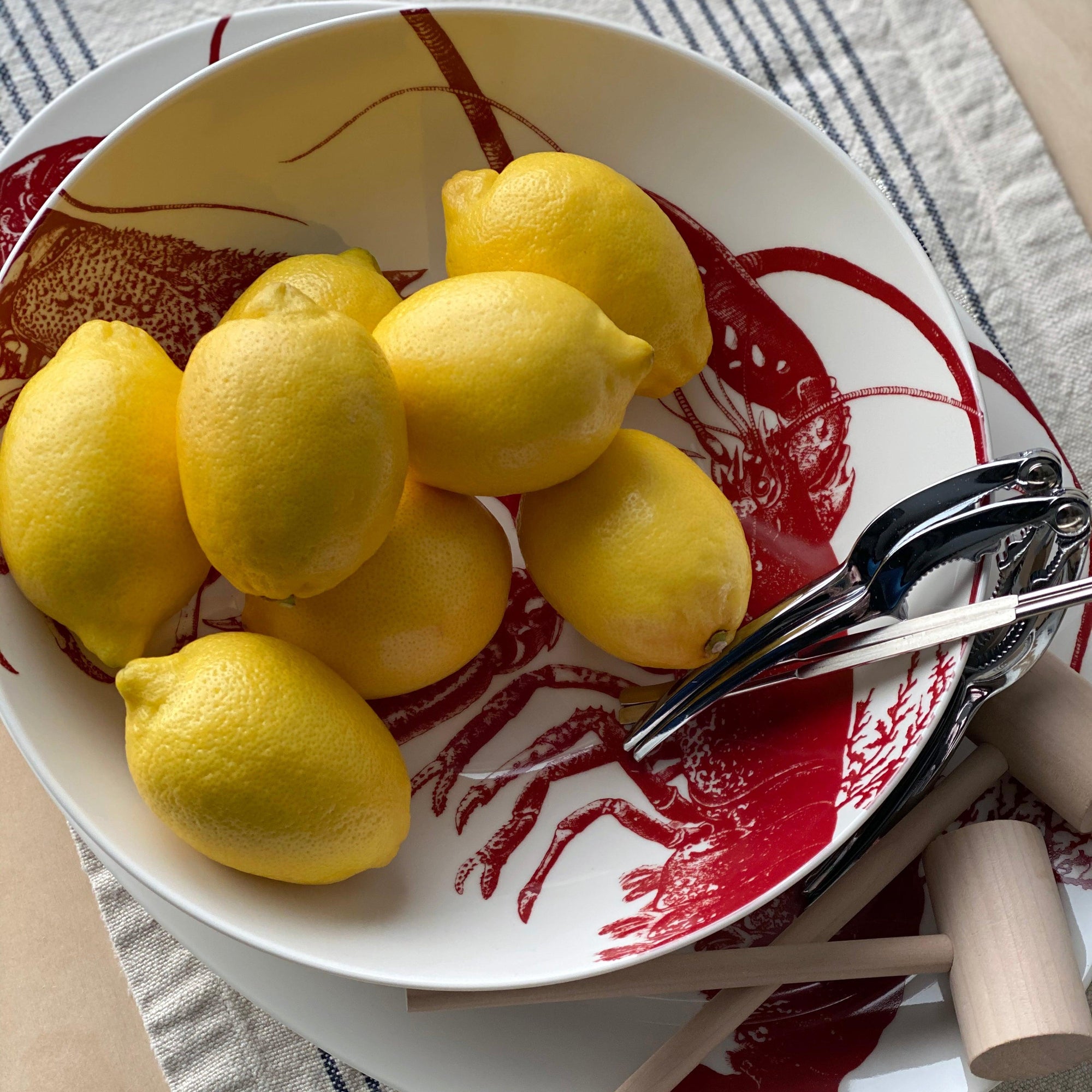 A white ceramic Lobster Wide Serving Bowl by Caskata Artisanal Home featuring a red illustration of two lobsters facing each other, perfect for adding a touch of seaside style tableware to your dining experience.