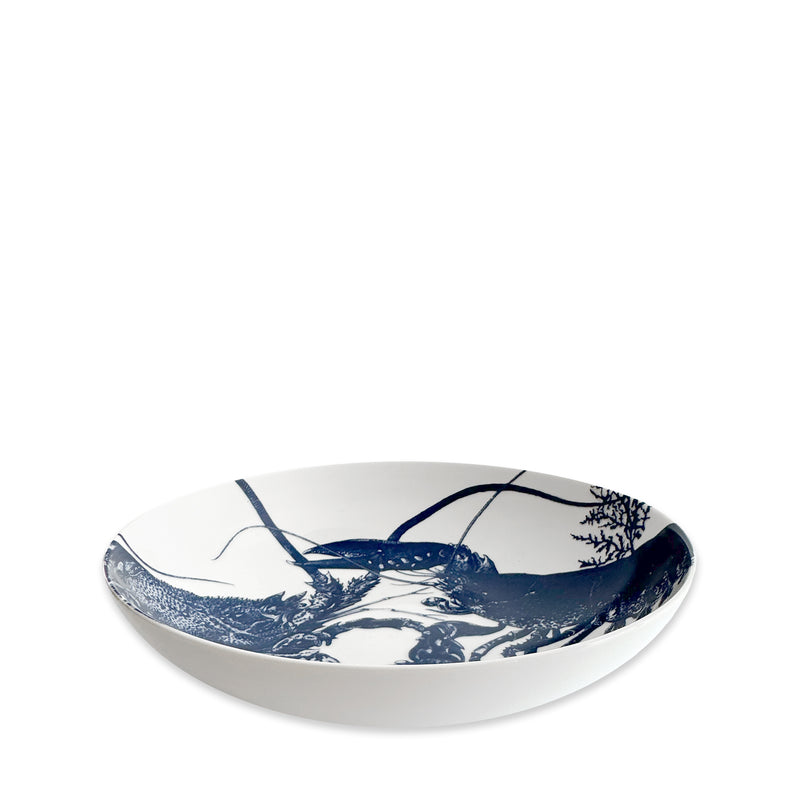 The Caskata Lobster Entrée Bowl is a white porcelain bowl featuring a blue, nature-inspired design inside. This elegant bowl is also dishwasher safe.