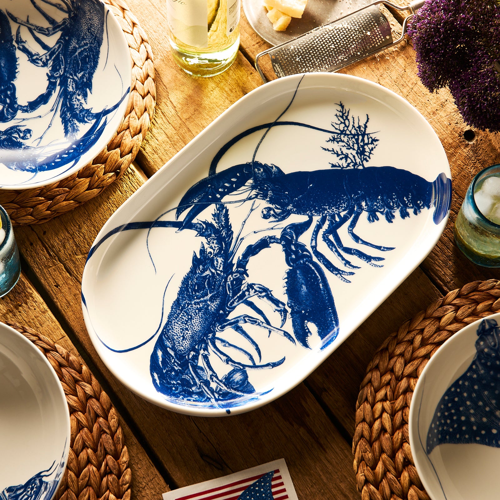 The Caskata Lobster Large Coupe Oval Platter features detailed blue lobsters with seaweed accents on white porcelain—a striking serveware piece perfect for entertaining.