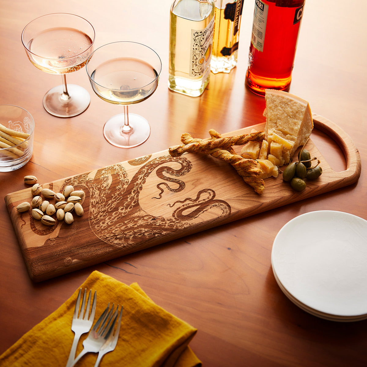 A charming octopus is perched gracefully on a Lucy Serving Board made of cherry wood, designed by Caskata.
