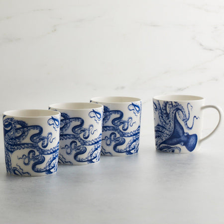 Four Caskata Artisanal Home Lucy Mugs featuring blue octopus designs are lined up on a light surface with a white marble background—the perfect coastal drinkware addition to your collection.