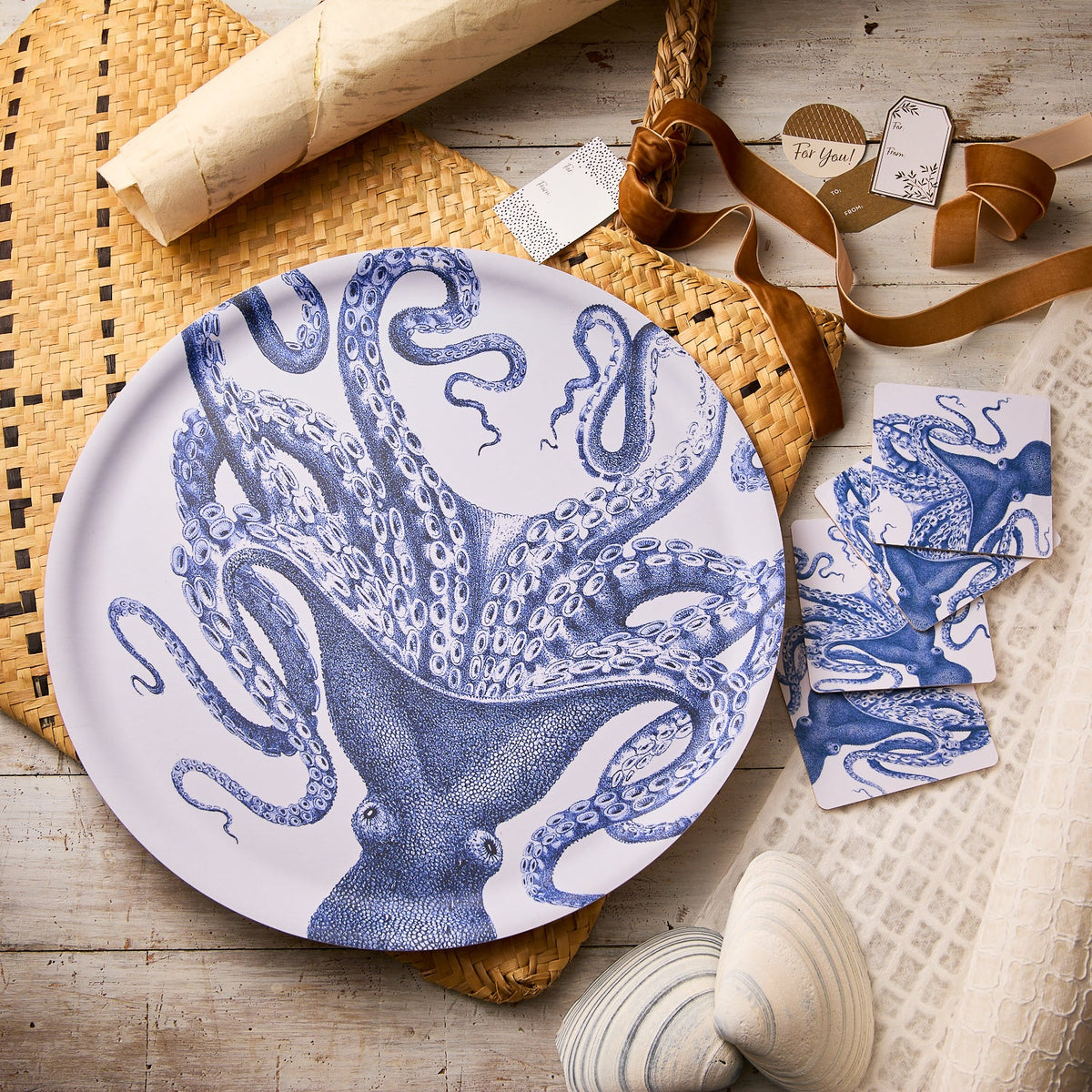 The Caskata "Lucy Al Fresco" Bundle features a round birchwood tray with a blue octopus design and matching coasters—a perfect ocean-themed gift set for sea lovers.