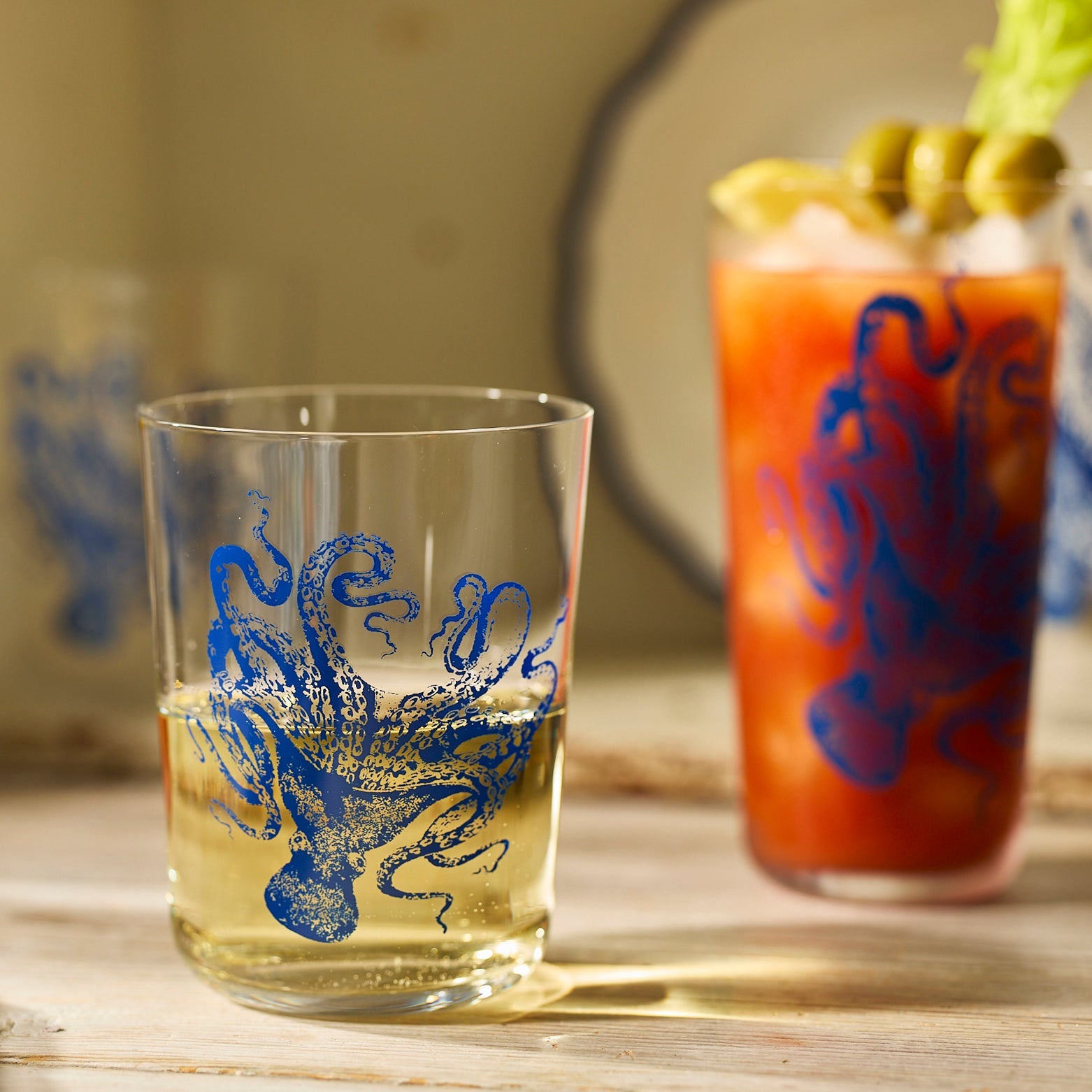 Four Caskata Lucy Blues Short Drinking Glasses, crafted from lead-free crystal and featuring blue octopus illustrations, are displayed in two rows against a white background.