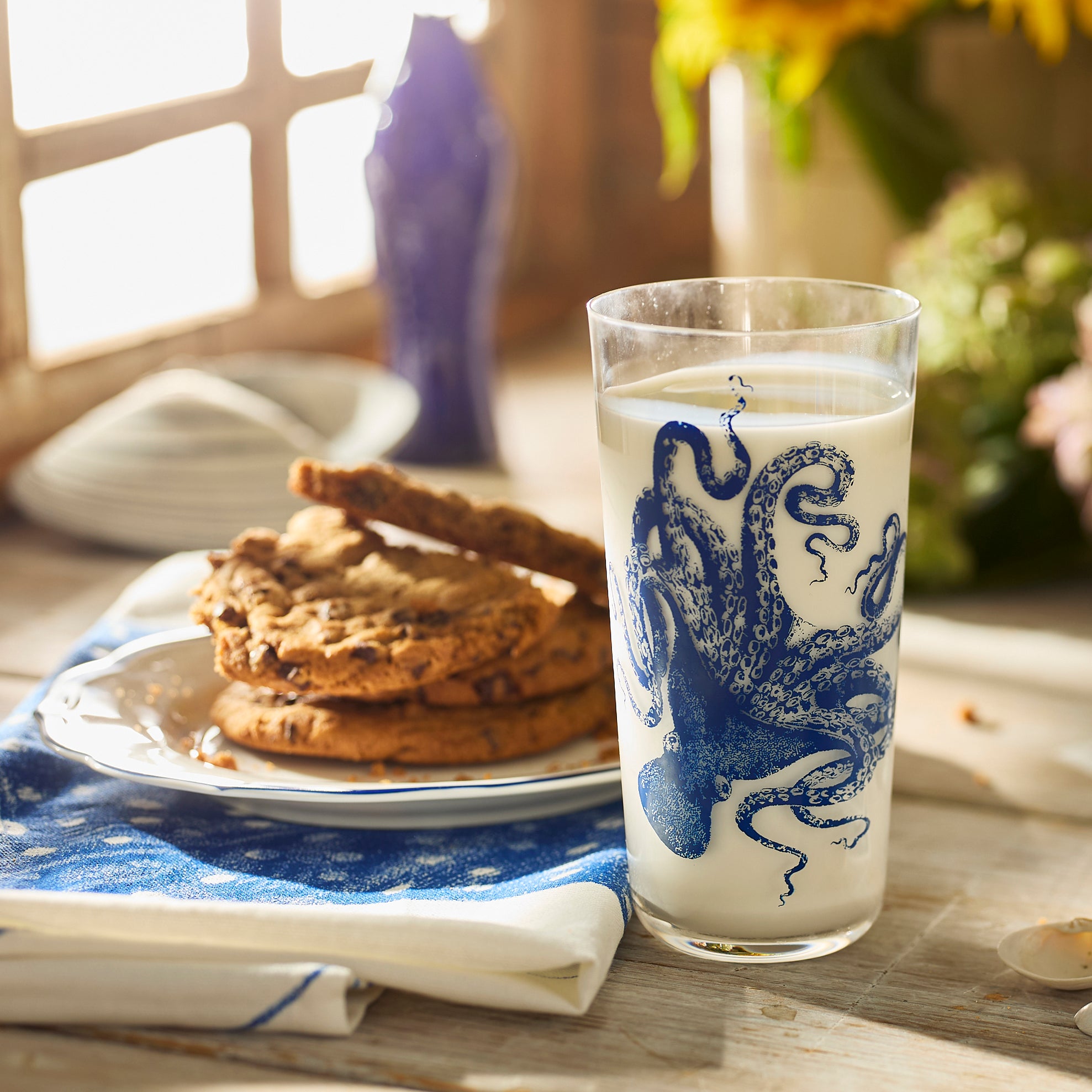 Four Caskata Lucy Blues Tall Drinking Glasses featuring blue octopus designs, inspired by Lucy the octopus, are arranged together on a white background.