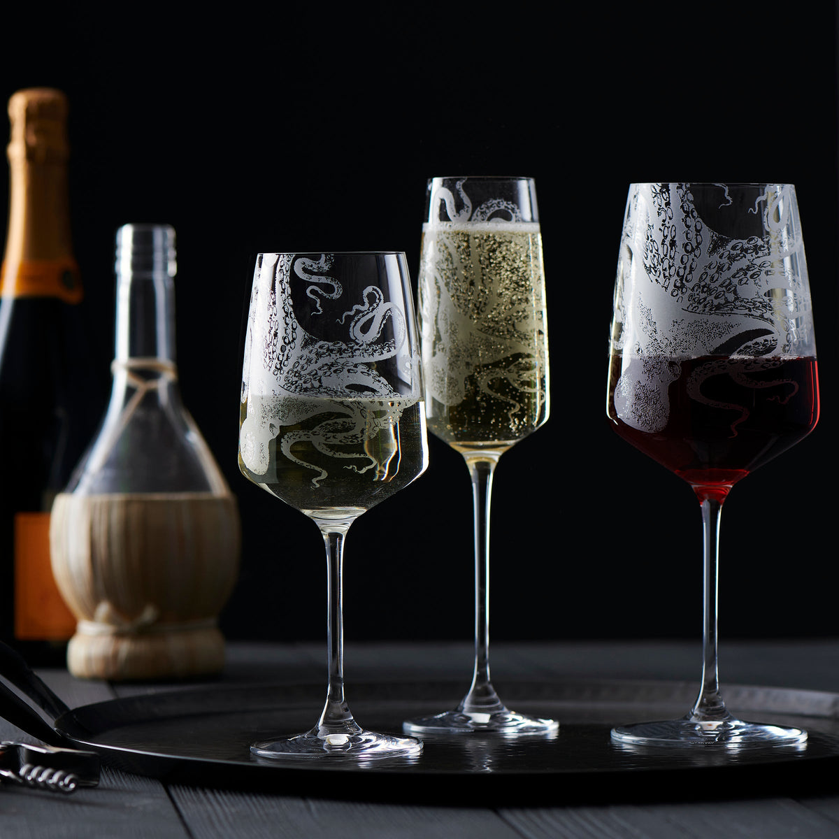 A tray with Lucy Champagne Glasses from Caskata Artisanal Home and a bottle of wine.
