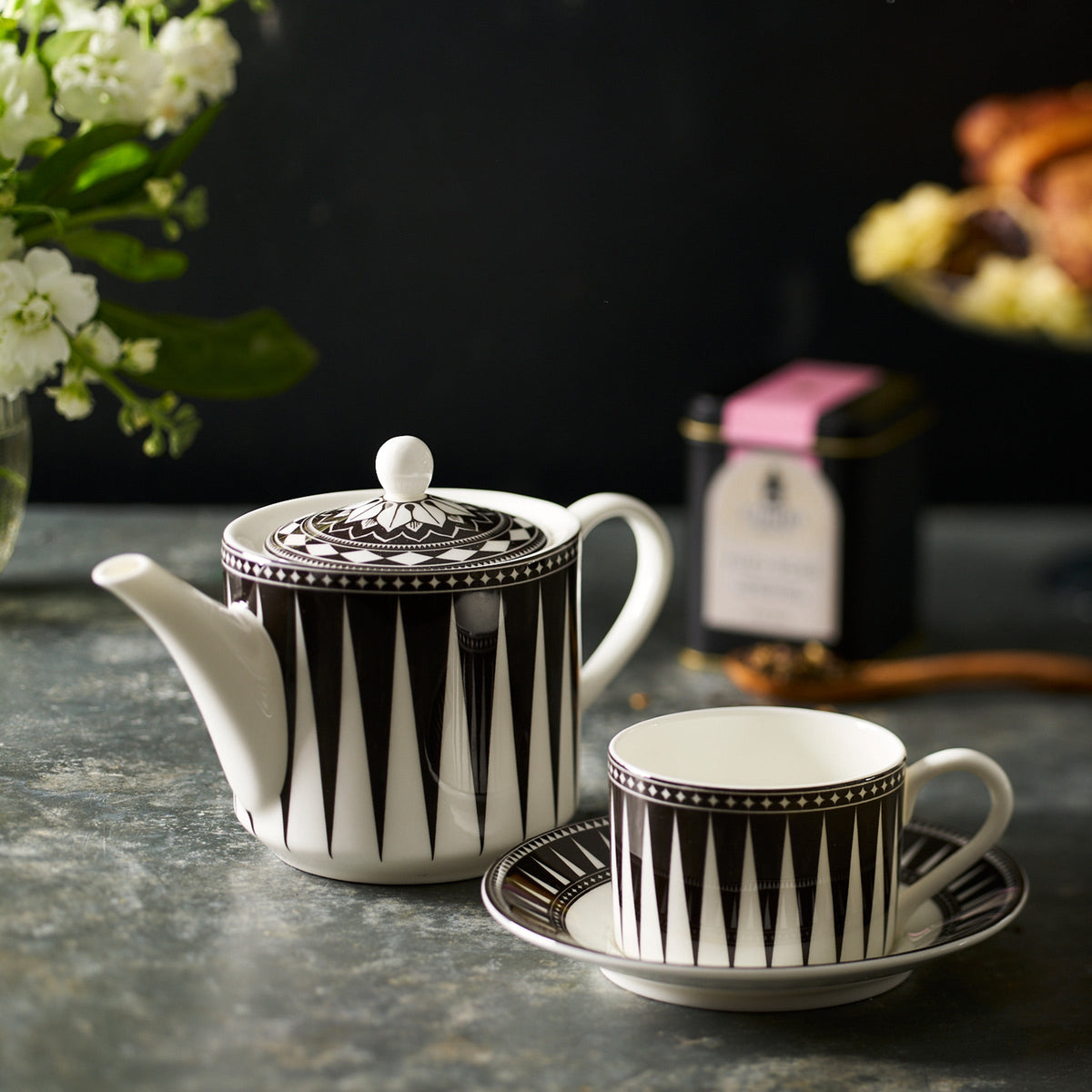 A Caskata Marrakech Petite Teapot and saucer on a table, made of bone china.