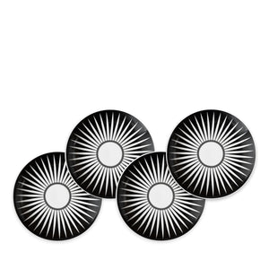 Four Marrakech Small Plates by Caskata Artisanal Home, each made of high-fired porcelain with white radial starburst patterns, are arranged in a staggered overlapping formation reminiscent of Marrakech's intricate designs.