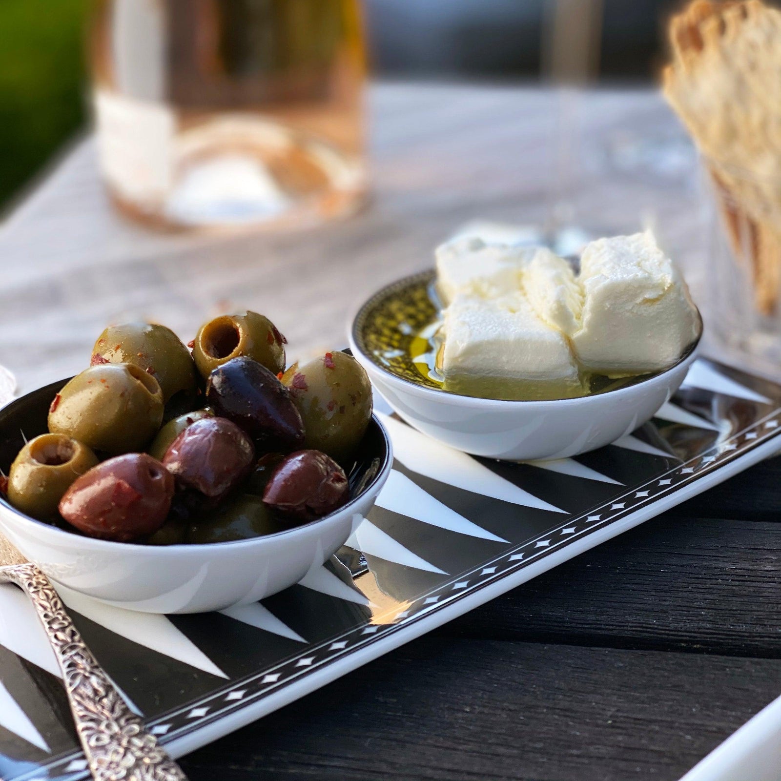 The Marrakech Petite Serving Tray by Caskata is a rectangular ceramic platter featuring a black and white geometric harlequin pattern, reminiscent of vibrant Art Deco style.