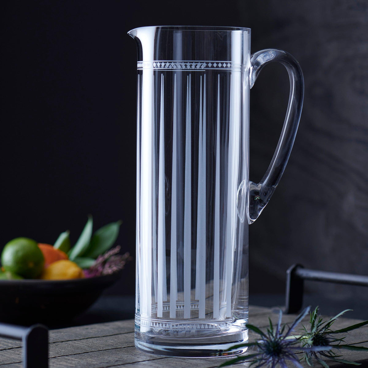 A Marrakech Tall Pitcher by Caskata Artisanal Home with graphic patterns sitting on a table next to some fruit.