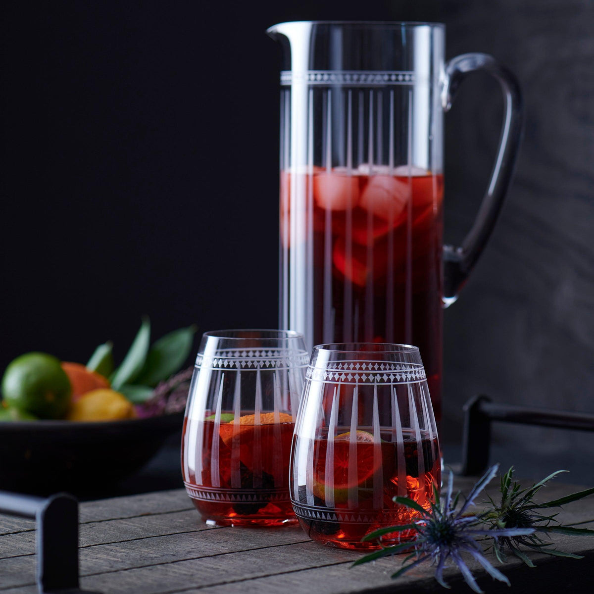 A Marrakech Stemless Wine Glasses and a pitcher of wine with graphic patterns on a table inspired by Art Deco forms in Marrakech, all by Caskata Artisanal Home.