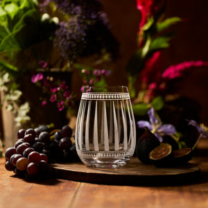 The Art Deco Bar Bundle by Caskata features a clear, stemless wine glass with vertical etched lines—an elegant piece to enhance your barware collection. Grapes, figs, and flowers complete the sophisticated look.