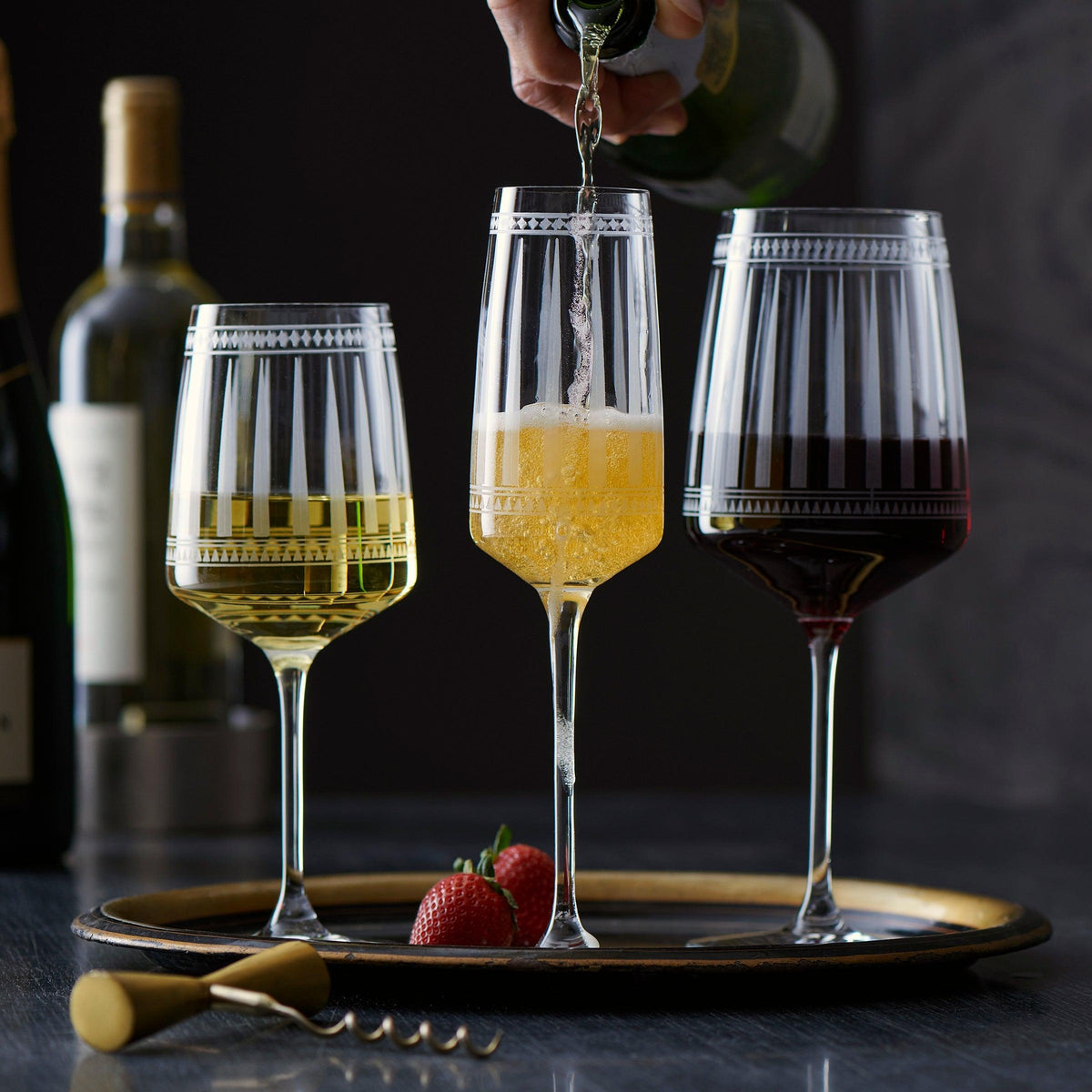 A person pouring red wine into Marrakech Red Wine Glasses on a tray in Caskata Artisanal Home.