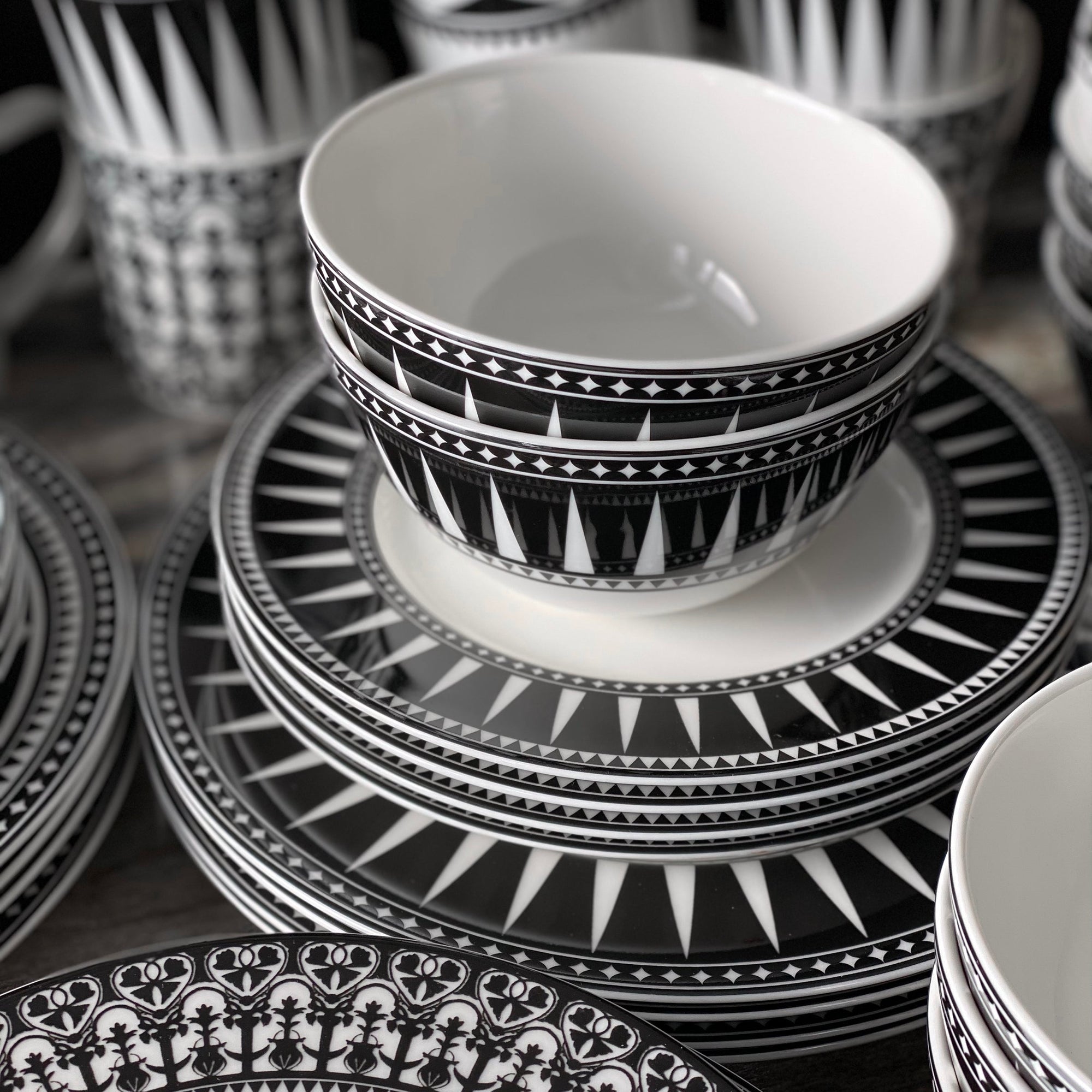 The Caskata Marrakech Table for 4 porcelain dish set features black and white Art Deco plates and bowls—four large plates, four small plates, and four bowls—elegantly displayed on a white background.