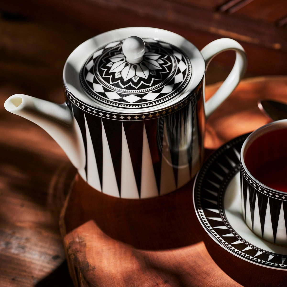 A Marrakech Petite Teapot and saucer by Caskata on a wooden table.