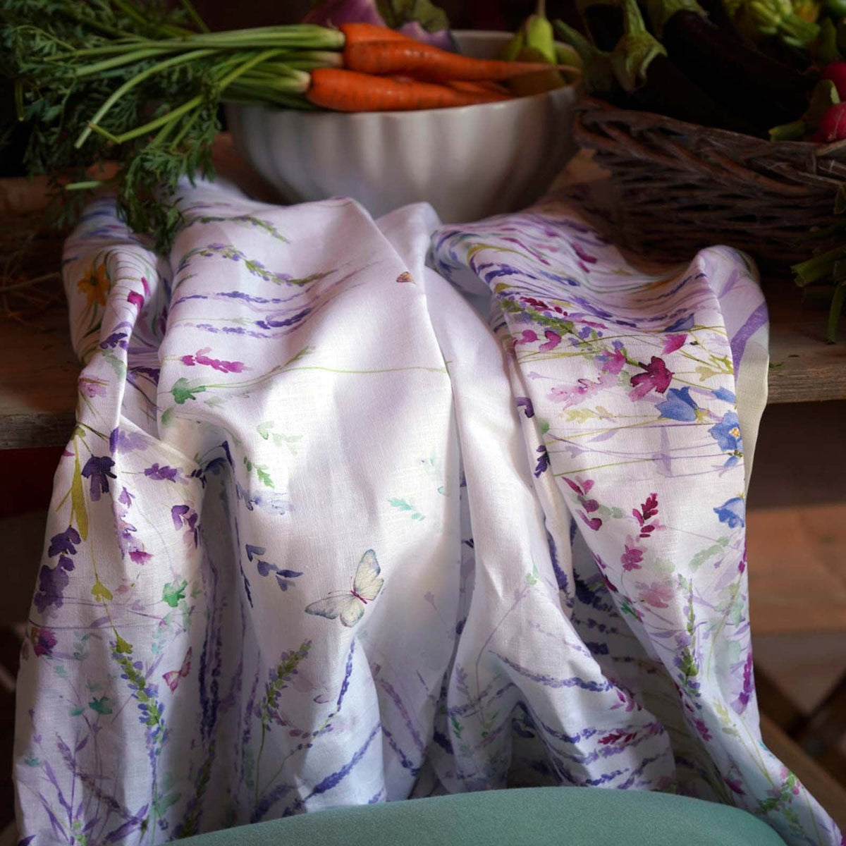 Meadow Tablecloth featuring delicate floral watercolors with butterflies in shades of purple,green, and blue on Italian linen from Caskata