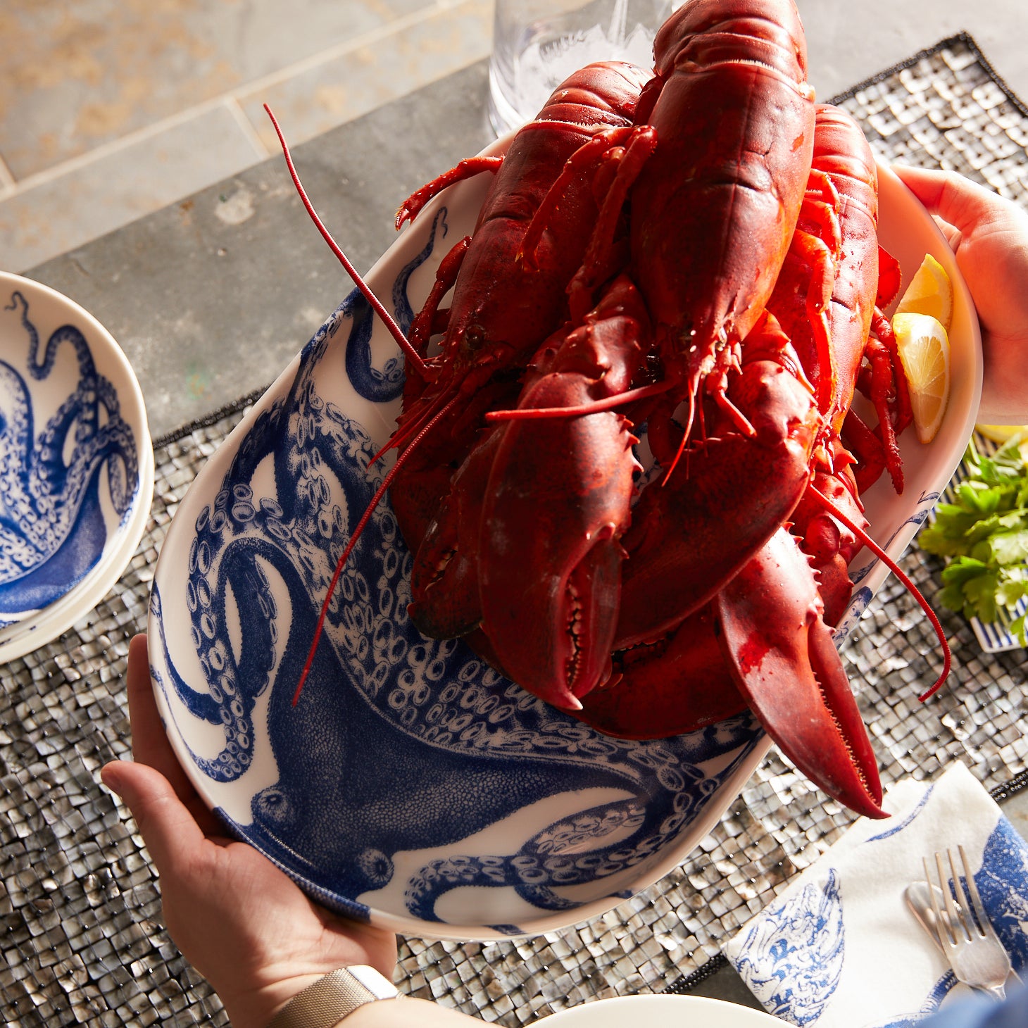 The Caskata Lucy Crudité Set features a white ceramic platter and bowl with blue octopus illustrations, adding coastal charm and seaside elegance to your table. Perfect for gatherings or as stylish home decor.