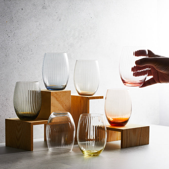 A collection of various colors of Quinn mouth-blown tumbler / stemless wine glasses from Caskata.